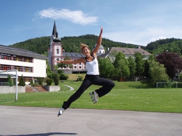 晴天の青空の屋外でインラインフィギュアスケートでジャンプしている女性の写真画像