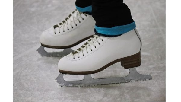 記事タイトル「フィギュアスケートの靴職人さんやメーカーについて」のイメージ画像。スケートリンク上に立っている女の子の白いアイスフィギュアスケート靴の画像